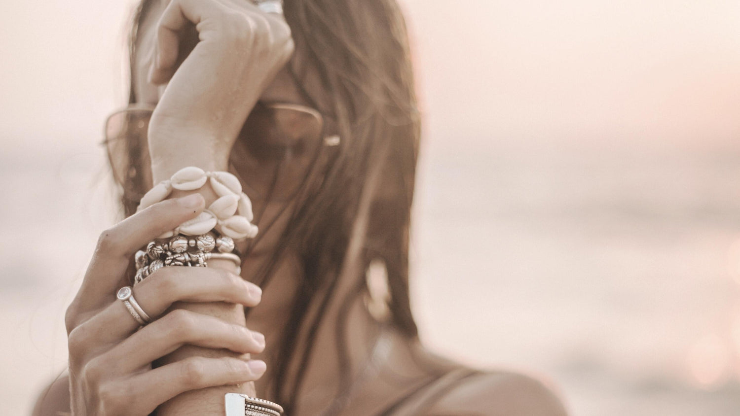 Eine Frau am Strand trägt mehrere Heilsteinarmbänder von MANA'OLANA® – Schmuck für Harmonie, Balance und natürliche Eleganz.